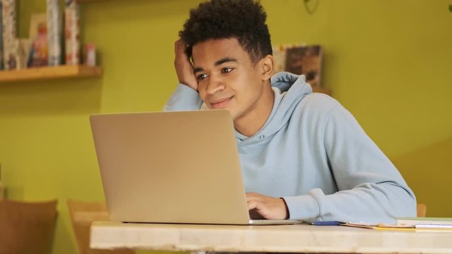Serious handsome african guy student studying doing homework using laptop computer.