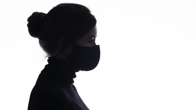 silhouette profile confident young woman in a protective mask on white isolated background, girl fearlessly looking straight and resist the wind, concept power, life problems