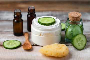 Obraz na płótnie Canvas Concept of natural organic ingredients in cosmetology and home beauty treatment. Moisturizing gentle cream, mask, essential oils for radiant shiny skin. Fresh cucumber, wooden background