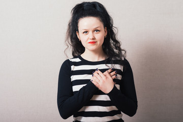 Woman holding hands on the heart. Gray background