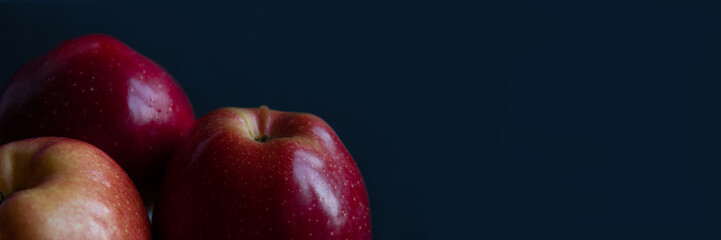 Red, juicy apples isolated on a black background. Dark food photography. Banner. Selective focus. Side view