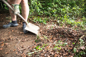 Man shovelling garden waste leaves with a shovel © Mara Louvain