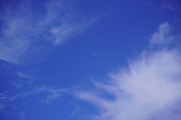 Naklejka na ściany i meble White light fluffy clouds in a blue sky with a solar flare.