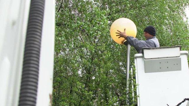 Worker in lift bucket repair street light. People change the lamp on a street lamp