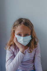 a sad girl in quarantine with a mask looks with blue eyes. portrait close-up. covid