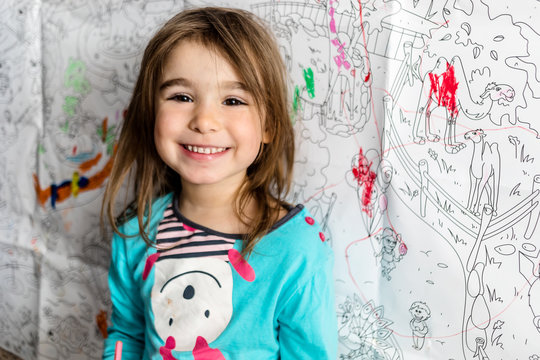 Cute little girl coloring on her wall at home.