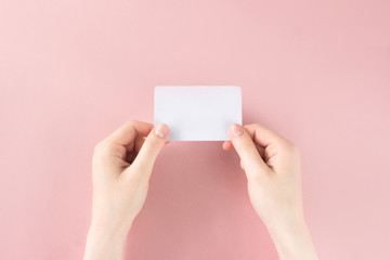 Female hand holding white business card on colorful pink background. Template, mockup, blank for web, social media, advertisement with copy space. Marketing, business branding. Stock photo.