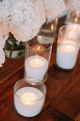 Flower arrangement, crystal, glass candles decorate banquet hall. White hydrangea and candles.