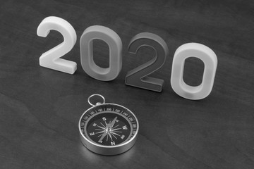 Obraz na płótnie Canvas Business directions in 2020 or travel industry in 2020 theme, numbers 2020 and compass on wooden background.