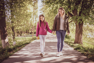 Young mother with baby walking in park near river. Spring morning. They look at each other