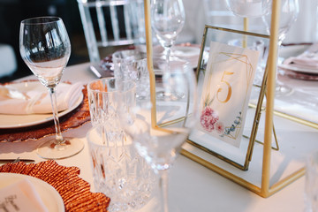 Wedding. Banquet. White table with pink and white flowers and red and white plates on it, served with cutlery, flowers and crockery and candles.