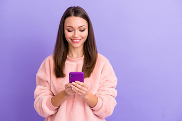 Fototapeta premium Photo of cheerful blogger lady holding telephone hands texting friends discuss meeting gathering party wear casual fur fluffy pullover isolated purple color background