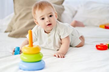 Close-up, a little baby crawls on all fours to a toy on the bed.