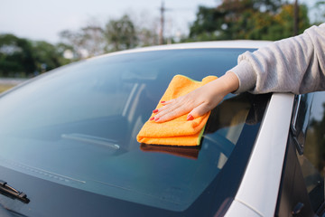 A woman cleaning car with microfiber cloth, car detailing (or valeting) concept