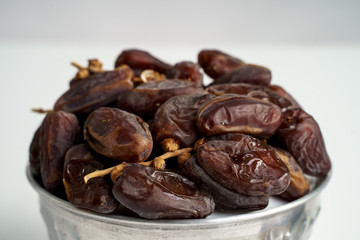Dates fruit in the bowl on white background. Medjool dried date palm fruits