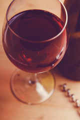 Glass of red wine with a bottle on a wooden background