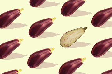 Flat lay colorful pattern with eggplant on pastel yellow background. Trendy mockup or wallpaper. Minimal healhty lyfestyle concept with sharp shadows.