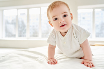 Close-up. A baby learns to crawl while standing on all fours on the bed.