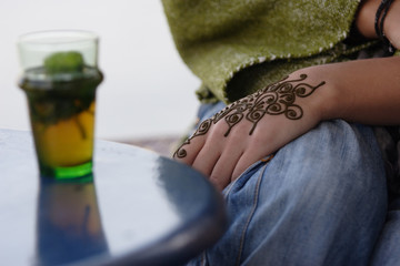 A hand painted with Moroccan henna holding a green tea
