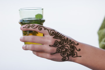 A hand painted with Moroccan henna holding a green tea