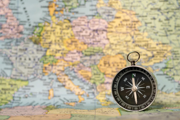 A compass in front of a map of Europe.