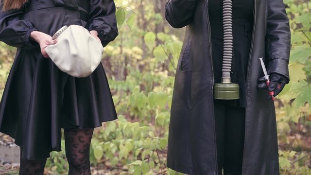 man in black clothes gives a girl's gas mask from hand to hand