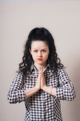 Closeup portrait of a young woman praying, isolated on a gray background