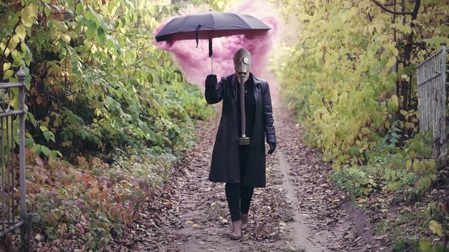 A girl in a black leather coat with a black zante and a gas mask. Purple smoke comes from under the umbrella