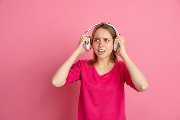 Fototapeta premium Listen to music, shocked. Caucasian young woman's portrait isolated on pink studio background, monochrome. Beautiful female model. Concept of human emotions, facial expression, sales, ad, trendy.