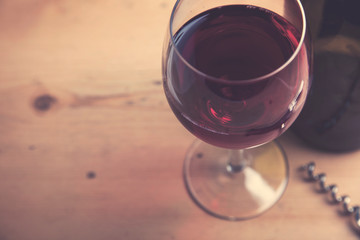 Glass of red wine with a bottle on a wooden background