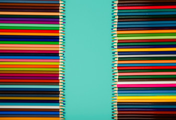 Colored pencils of all colors of the rainbow on blue background