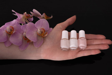 on a female palm lies nail polish and an orchid