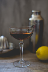 alcohol whiskey cocktail in a coupe glass with lemon and shaker