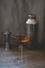 alcohol whiskey cocktail in a coupe glass with lemon and shaker