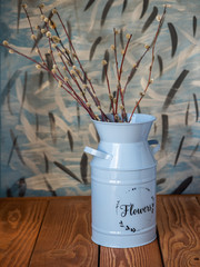 Decorative bouquet with verbs of blooming willow in a high planter on a brown table