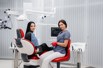 The dentist shows a picture of the patient's teeth and tells the necessary treatment. Dentistry, health.