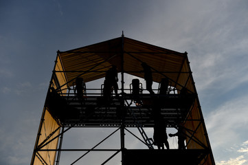 Technical staff and equipment silhouetted against sunset light preparing for a music concert