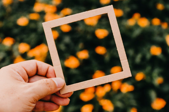 Hand Holding Blank Paper Frame With Nature Bokeh Background