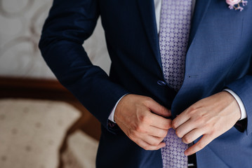 Stylish young man buttoning the cuff links on the sleeves. Style