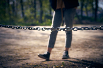 Stop Concept. Selective focus on a metal chain in front of a girl silhouette. Blurred background