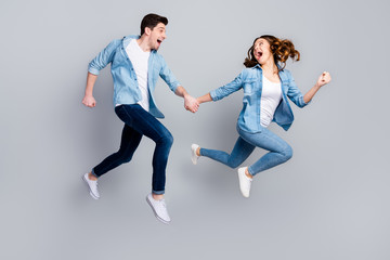 Fototapeta na wymiar Full size photo of cheerful funky students spouses enjoy spring weekend rest jump hold hand run moving wear casual style outfit gumshoes isolated over gray color background