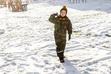 Fototapeta na wymiar Baby boy aims a snowball at a friend. Games on the Playground in winter.