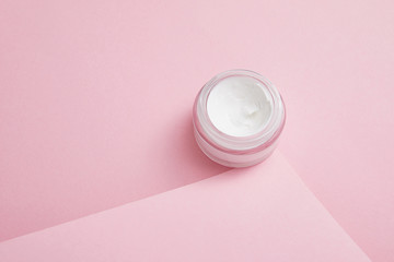 Cosmetic cream in glass jar on pink background