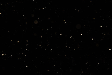 Small white snowflakes fall from the night sky. Snowfall in winter on a black background.