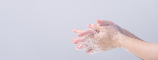 Fototapeta premium Washing hands. Asian young woman using liquid soap to wash hands, concept of hygiene to protective pandemic coronavirus isolated on gray white background, close up.