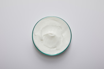 Top view of laboratory glassware with white cosmetic cream on grey background