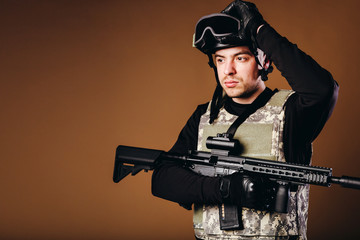 Soldier with gun is standing on brown background. Concept of war. Veterans, comrades, soldiers. Man...