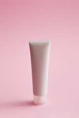 Plastic cosmetic cream tube on pink background