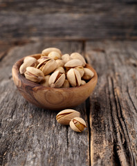 Pistachio nuts in  the wooden bowl  on a wooden background.