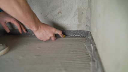 Worker glues damper tape before laying the floor. Reinforcing tape for drywall. Damper tape for screed